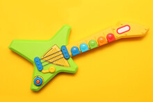 Children's Toy Guitar On A Yellow Background, Top View, Kindergarten.