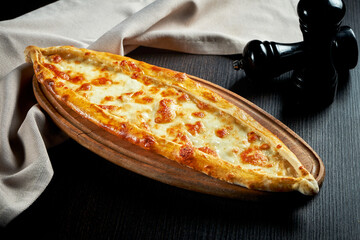 Wall Mural - Turkish pide dish with tomatoes and salted cheese on black background