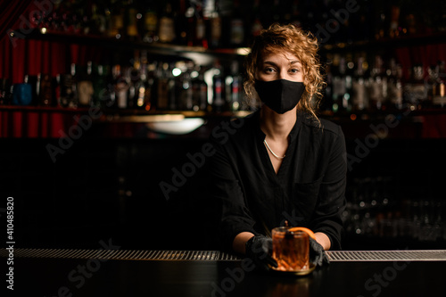 view of handsome young woman in black mask and black gloves at bar