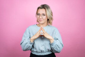 Wall Mural - Young caucasian woman wearing sweatshirt over pink background with Hands together and fingers crossed smiling relaxed and cheerful. Success and optimistic