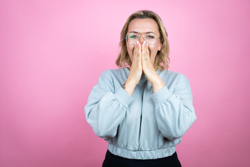 Wall Mural - Young caucasian woman wearing sweatshirt over pink background shocked covering mouth with hands for mistake. secret concept.