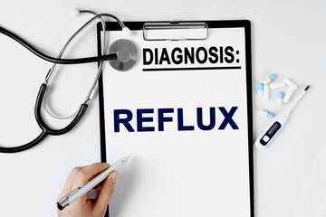 On the table are a stethoscope, a pill thermometer, and a diagnosis sheet. The text is written on the sheet with the diagnosis - REFLUX