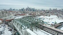 Snowy Winter Day Flying Over Elevated Train In Brooklyn As It Moves Towards NYC Skyline