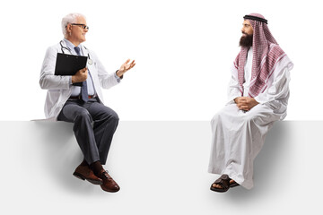 Canvas Print - Mature doctor sitting on a blank panel and talking to a saudi arab man