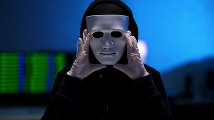Wall Mural - unrecognizable man in black clothes holding anonymous face mask. hacker in white gloves indoors in b