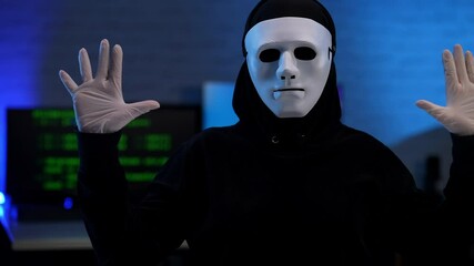 Wall Mural - unrecognizable hacker in anonymous face mask raising hands up. masked panicked coder arrested in blu