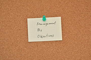 A piece of paper labeled Management by Objectives is pinned to the corkboard.