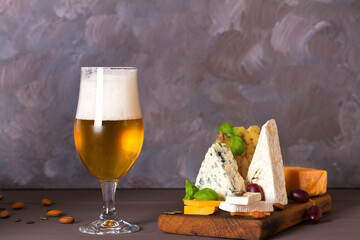 Wall Mural - Beer and cheese. Glass of beer with cheese and walnuts. Ale and food concept. Copy space