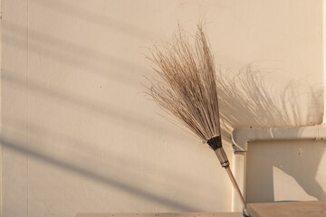 A coconut broom sticks inside garbage bin, at the wall. Landscape size.