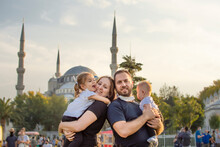 Portrait Of Happy Tourist Family In Mask In Front Of Blue Mosque Istanbul, Turkey. Tourism Back To Turkey After Covid-19 Lockdown. Cute Mother, Father, Daughter, Son Travel Together, Posing For Photo