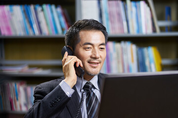 Wall Mural - asian corporate executive working in office talking on phone