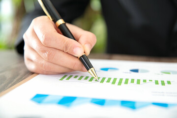 Wall Mural - Close up with a pen in hand looking at the financial trend chart