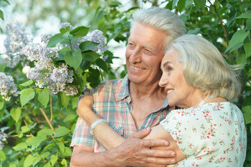 beautiful senior couple hugging   in the park by lilacs