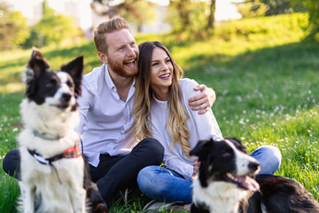 Wall Mural - Happy couple playing with dog in the park outdoor