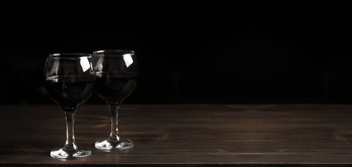 Glasses of red wine on a wooden table. Against the background of darkness