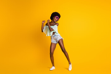 Wall Mural - Full length body size photo of black skinned girl wearing stylish summer clothes dancing on dance floor isolated on bright yellow color background