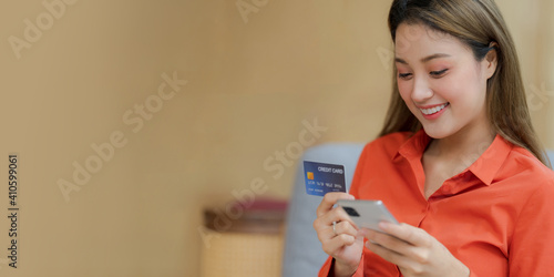 Portrait of Happy woman holding smart phone with credit card and smiling face in creative office © Naypong Studio