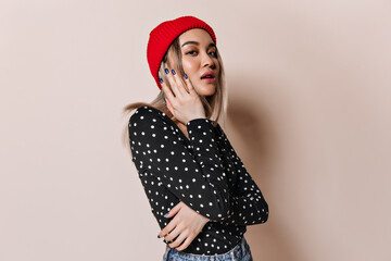 Wall Mural - Blonde girl in bright hat looks into camera on isolated background