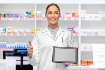 Sticker - medicine, profession and healthcare concept - happy smiling female doctor or scientist in white coat with tablet pc computer showing thumbs up over pharmacy background