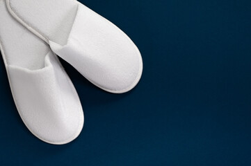 White slippers on a blue background with empty space. Slippers for guests. View from above.