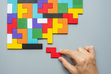 hand connecting geometric shape block with colorful wood puzzle pieces. logical thinking, business logic, Conundrum, decision, solutions, rational, mission, success, goals and strategy concepts