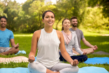 Sticker - fitness, sport, yoga and healthy lifestyle concept - group of people meditating in lotus pose at summer park