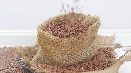 Sticker - View of dropping flax seeds over a brown bag filled with flax seeds