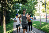 Fototapeta Las - Group of young people in sports clothing running in city park.