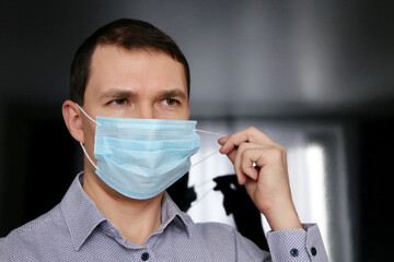 Man in office clothes removing medical face mask. Concept of violation of safety measures during coronavirus pandemic