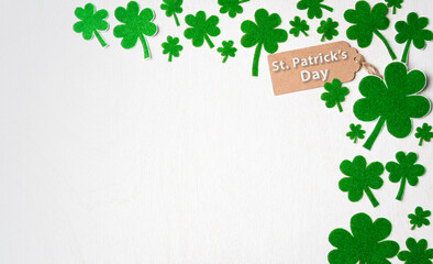 Wall Mural - Happy St. Patrick's Day concept, St. Patrick's greeting card with green paper clover leaf on white wooden background. Flat lay, top view with copy space.