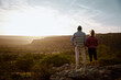 © StratfordProductions - Rear view of young man and woman standing at mountain cliff looking at sunrise