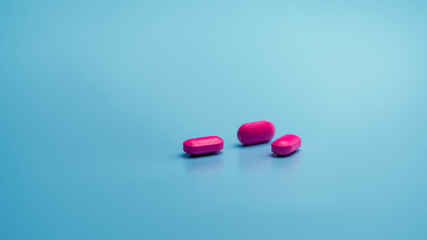 Canvas Print - Pink tablets on blue background. Painkiller medicine. Ibuprofen tablets pills. Pharmaceutical industry. Drug for treatment migraine headache. Community pharmacy product. Cancer pain management concept