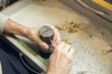 Wall Mural - Leveling. Close up hands of jeweller, goldsmiths making of golden ring with gemstone using professional tools. Craft production, precious and luxury jewel, hand made occupation. Workshop, artwork.