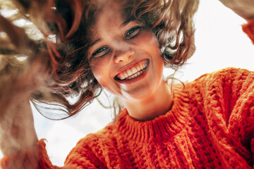 bottom view of a candid beautiful young woman wearing a knitted orange sweater smiling broadly and l