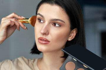 Wall Mural - Candid closeup portrait of a brunette young woman making makeup herself.