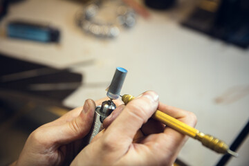 Wall Mural - Polishing. Close up hands of jeweller, goldsmiths making of silver ring with gemstone using professional tools. Craft production, precious and luxury jewel, hand made occupation. Workshop, artwork.