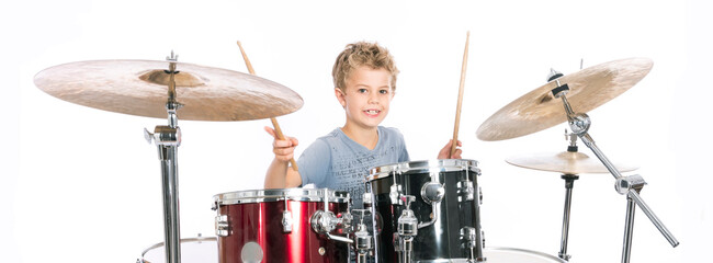 young caucasian boy plays drums in studio against white background