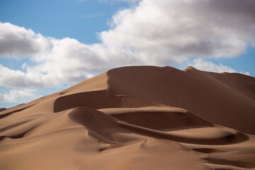 Golden sand dune 7 and white clouds on a sunny day in the Namib desert. Fantastic place for travelers and photographers