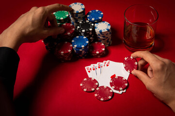 Casino. Poker. Hands of a gambler. Poker player. Game chips and dice lie on the table against a red background. Game chips for betting in gambling. Dice. Poker chips. 