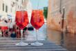 Two glasses of Spritz Veneziano cocktail served near the Venetian canal.  Popular italian summer aperitif drink. Venice background.