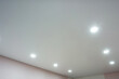 suspended ceiling with halogen spots lamps and drywall construction in empty room in apartment or house. Stretch ceiling white and complex shape.