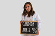 © fabio - Female doctor holds blackboard with candida auris written on it. Candida auris is the new world pandemic infection.