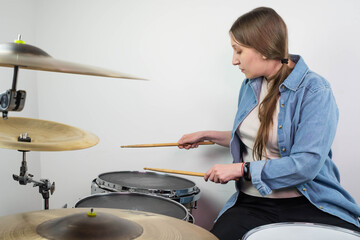 Professional drum set closeup. Beautiful young girl drummer with drumsticks playing drums and cymbals, on the live music rock concert or in recording studio. Female drummer.