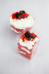 Wall Mural - homemade portioned dessert red velvet decorated with berries on a light wooden background