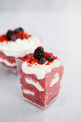 Wall Mural - homemade portioned dessert red velvet decorated with berries on a light wooden background