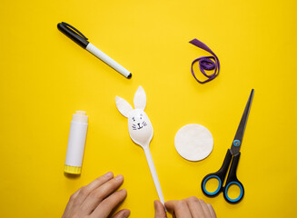 Making Easter bunny from plastic spoon and cotton pad on yellow background. Homemade easy children's craft. Simple creative art project.Step by step instructions.Decor for spring. DIY concept. Step 5