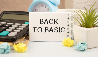 Notepad with text back to basics on table with chopsticks, colored paper clips and crumpled sheets.