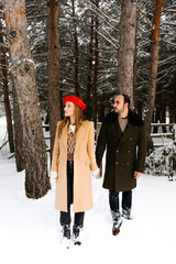 pareja joven abrigada feliz abrazándose en el exterior en bosque en un día frio de invierno