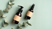 Organic Natural Cosmetic Products With Eucalyptus Leaves On Green Background. Amber Glass Spray Bottle And Liquid Soap Dispenser. Bathroom SPA Beauty Products Packaging Design.