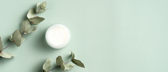 Wall Mural - jar of organic cream with eucalyptus leaves on green background. flat lay, top view, copy space. nat